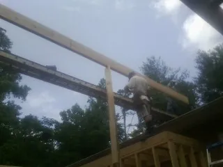 Carpenter setting a ridge beam over a new addition frame — Ice Dam Removal by Roofing Brothers in Cedar Springs