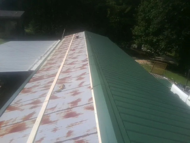Old rusted panels beside newly installed green metal roofing — Wind Damage Roof Repair by Roofing Brothers in Cedar Springs