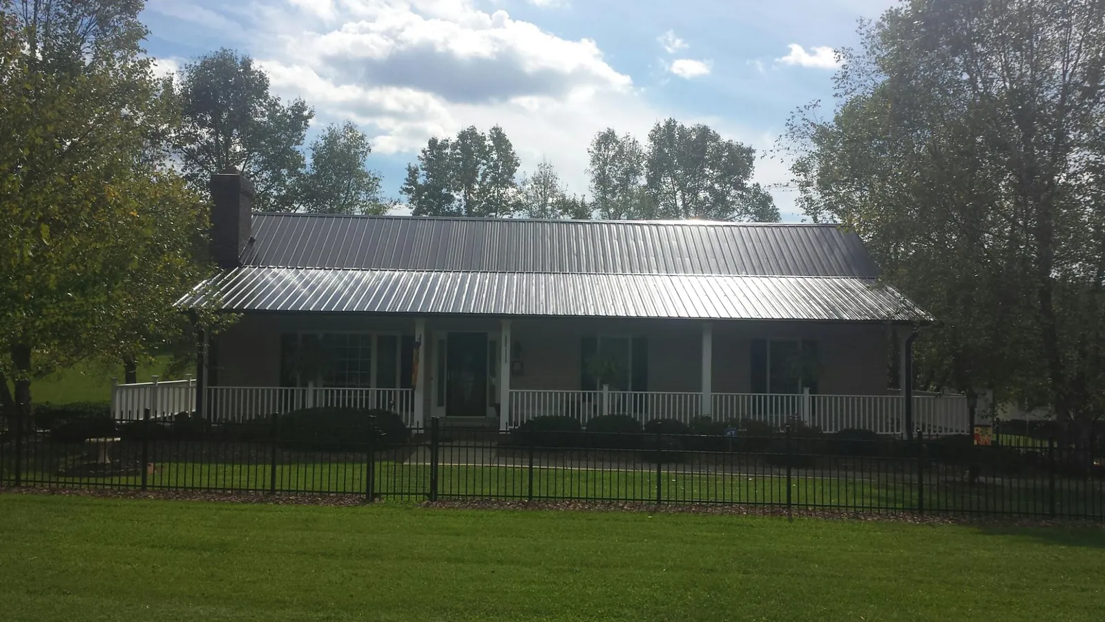 Gray metal roof on a brick ranch with a full width front porch — Gutter Guard Installation work by our crew in Cedar Springs